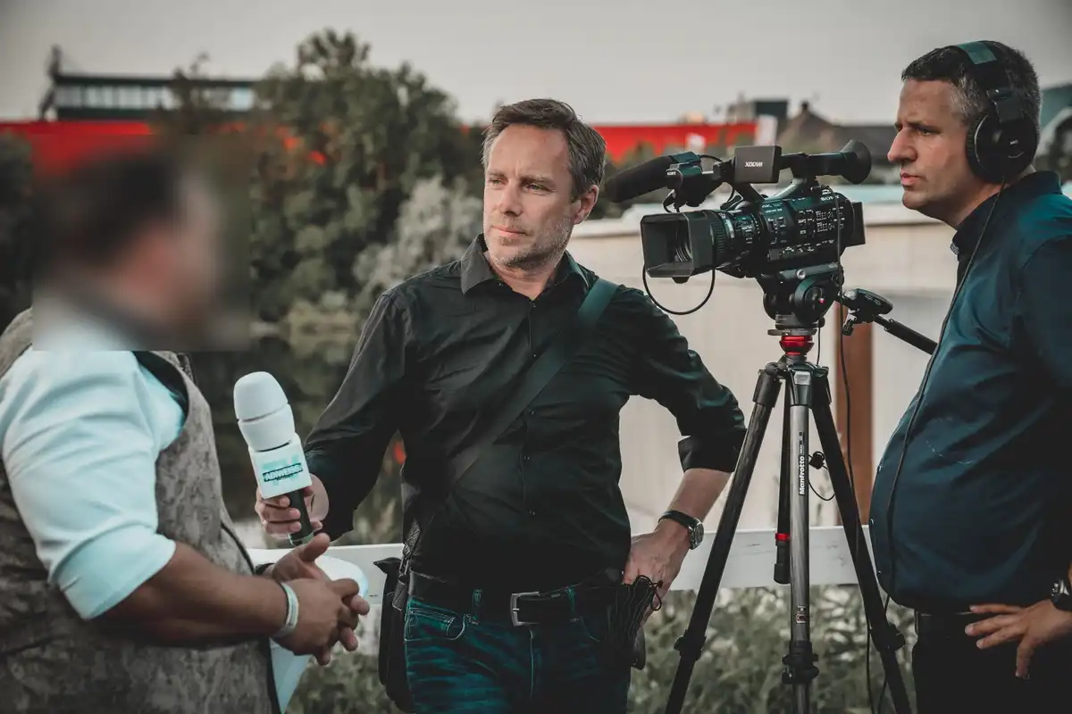 picture of a reporter taking an interview where the participant's face has been blurred.